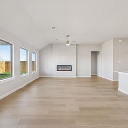 Lillian Homes - An open living area with a fireplace in the center.
