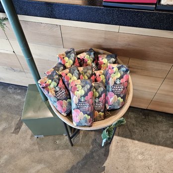 Starbucks - A basket containing Starbucks Thanksgiving Blend coffee bags is placed on a stand near a counter with various items in the background. - Coffee & Tea Near Me - Leander, Texas