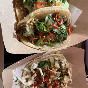 Taco Bamba Springfield - Two tacos with meat, chopped vegetables, and sauces, served in paper trays, featuring red and green peppers, lettuce, and creamy toppings. - Tacos Near Me - Springfield, Virginia