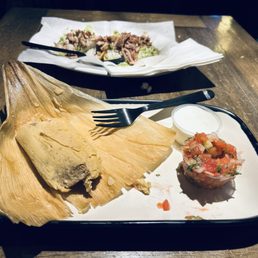 Pork tamale in husk front w tomato & white cream plus 2 corn tacos loaded carnitas, chicken meat.