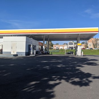 Shell - A Shell gas station features a canopy covering fuel pumps, vending machines, and a small building, with a parking lot and residential buildings in the background. - Gas Stations Near Me - Danbury, Connecticut