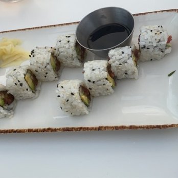 Offshore Rooftop - Sushi - A plate of sushi rolls with avocado and fish, accompanied by soy sauce, wasabi, and pickled ginger, on a white table. - New American Near Me - Chicago, Illinois