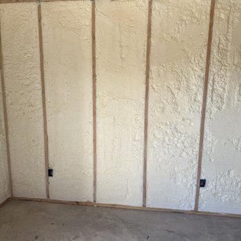 JC Insulation - Shed insulation - The image shows a room with unfinished walls insulated with spray foam insulation, with visible wooden framing and electrical outlets. - Insulation Installation Near Me