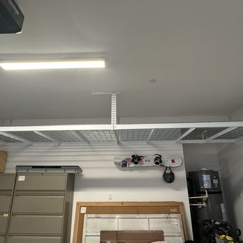 Topp Rax - Interior storage room with ceiling-mounted fluorescent light, metal shelving units, skateboard mounted on the wall, and a water heater in the corner. - Home Organization Near Me - Riverside, California