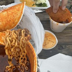 The noodles in a Tapatio bowl and the quesabirria taco getting dunked.