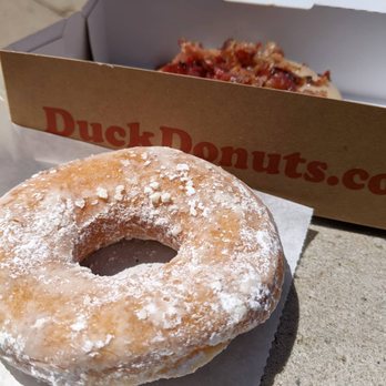 Duck Donuts - Powdered sugar donut and maple bacon in the background - Donuts Near Me - State College, Pennsylvania Duck Donuts - Powdered sugar donut and maple bacon in the background - Donuts Near Me - State College, Pennsylvania