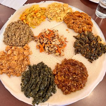 Zemam's - From top: yedoro alica, yetakelt wat, gomen wat, tilapia, spinach, spicy chicken, yesimir wat, and gomen alicha. Cauliflower in the middle. - Ethiopian Near Me - Tucson, Arizona