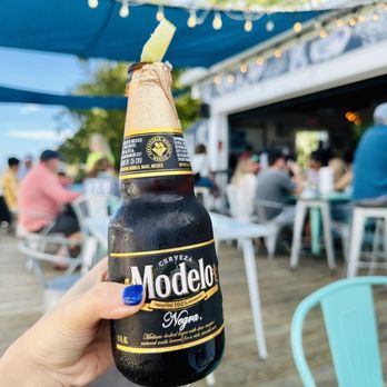 Half Shell Dockside - a person holding a bottle of mondelle - Bars Near Me - Apalachicola, Florida