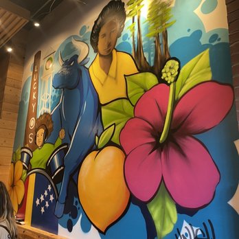 Boricua Soul - a woman sitting in front of a mural - Soul Food Near Me - Durham, North Carolina