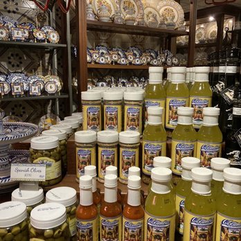 The Columbia - Store shelf with Columbia brand salad dressing, hot sauce, and Spanish olives, with decorative ceramic plates in the background. - Spanish Near Me - St Augustine, Florida
