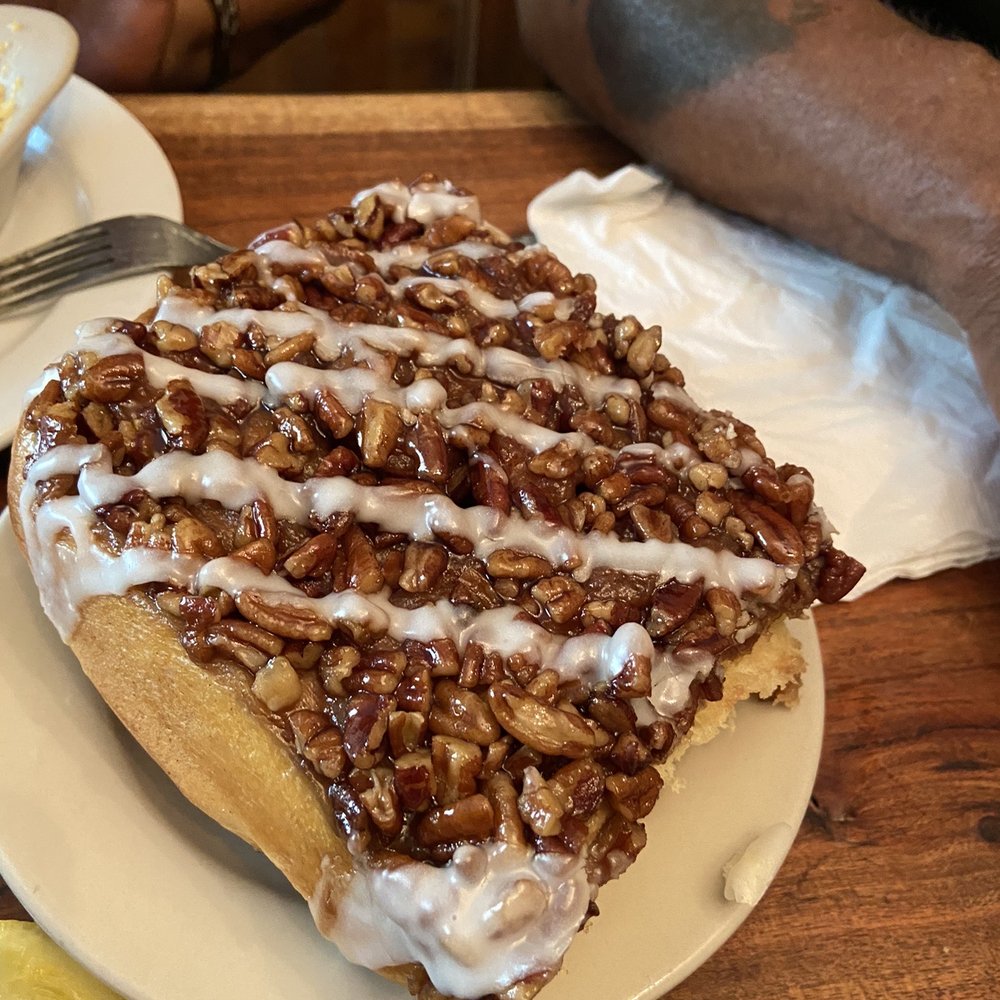 a slice of cinnamon roll with icing and pecans