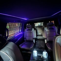 Spacious Cadillac Escalade ESV interior with captain seating, ambient lighting, and complimentary refreshments for executive transportation.