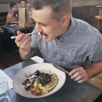 The Ice Plant - Someone stuffing their face with the best dish on the menu- short rib - Cocktail Bars Near Me - St. Augustine, Florida