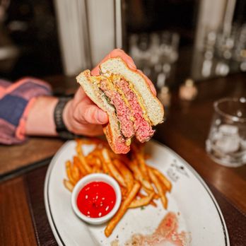 Oak Steakhouse - a hand holding a half eaten sandwich - Steakhouses Near Me - Highlands, North Carolina
