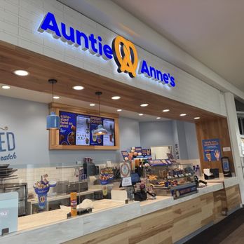 Brea Mall - Auntie Anne's pretzel shop in a mall features a lit sign, wooden accents, and a counter with menu displays and food items. - Shopping Centers Near Me - Brea, California