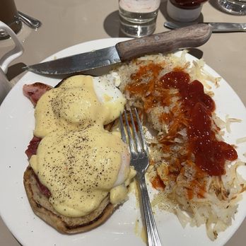 Elly's Pancake House - A breakfast plate featuring eggs Benedict with hollandaise sauce, hash browns topped with ketchup, and a knife placed on the plate. - Breakfast & Brunch Near Me - Norridge, Illinois