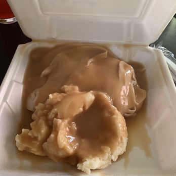 Trails Cafe - Open faced turkey sandwich - came with 2 additional sides - A foam takeout container is filled with mashed potatoes topped with brown gravy. The gravy covers the mashed potatoes and slightly overflows the edges of the container. The container is open, revealing the food inside, and is placed on a dark surface. The image focuses on the food presentation in a typical takeout setting. - Breakfast & Brunch Near Me - Gardner, Kansas