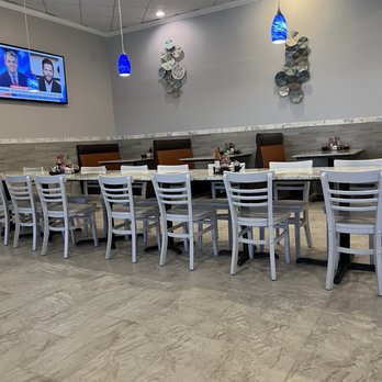 La Pho - a large dining room with white chairs and a flat screen tv - Vietnamese Near Me - Cypress, Texas