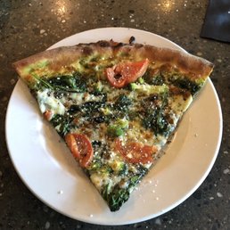 Pizza with spinach, broccoli, tomato, and pesto