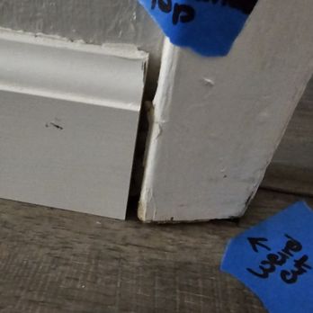 Express Flooring - A photo showing a damaged door frame with blue tape labels pointing to a cut in the wood or drywall. - Flooring Near Me - Rio Rancho, New Mexico