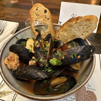 Uncorked Kitchen & Wine Bar - First course: Sauteed mussels with sausage, roasted garlic, tomatoes, served with crispy crostini - Venues & Event Spaces Near Me - Centennial, Colorado Uncorked Kitchen & Wine Bar - First course: Sauteed mussels with sausage, roasted garlic, tomatoes, served with crispy crostini - Venues & Event Spaces Near Me - Centennial, Colorado