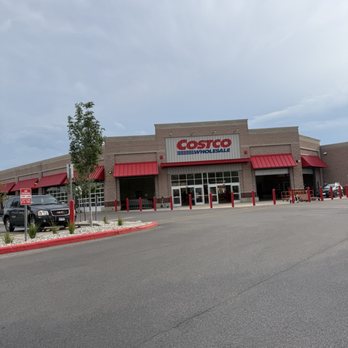 Costco - Storefront - The image shows the storefront of a Costco Wholesale in Chicago, IL, featuring a brick exterior with red awnings above the entrance. The parking lot in front has a few parked cars and landscaped areas with small plants and a tree. The sky above is cloudy, and the overall scene depicts a typical retail store exterior with clear signage and accessible parking spaces. - Wholesale Stores Near Me - Chicago, Illinois