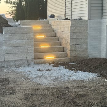 Millerz Construction - Beginning of a large patio with retaining wall and stairs with integrated hardscape lighting. - General Contractors Near Me Millerz Construction - Beginning of a large patio with retaining wall and stairs with integrated hardscape lighting. - General Contractors Near Me