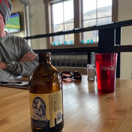 a man sitting at a table with a bottle of beer