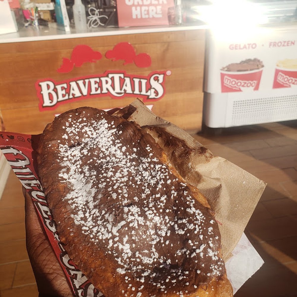 BeaverTails - a hand holding a pastry with powdered sugar - Desserts Near Me - Wasaga, Ontario