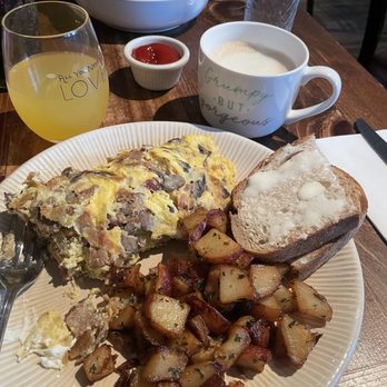 Petit Soleil - Mushroom Bacon Omelet, caramel & vanilla oatmilk latte, and a classic oj mimosa. In the background is the Corn Beef Hash - Breakfast & Brunch Near Me - Napa, California