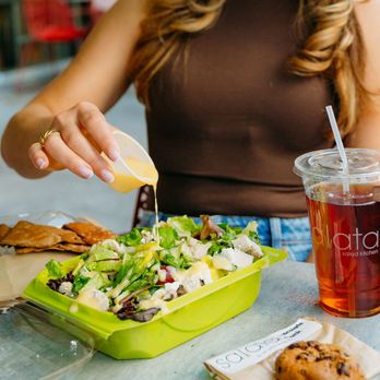 Salata - a woman sitting at a table eating a salad - Salad Near Me - Mesquite, Texas Salata - a woman sitting at a table eating a salad - Salad Near Me - Mesquite, Texas