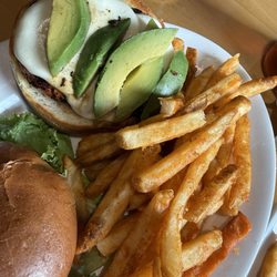 Grilled chicken sandwich with avocado and fries.