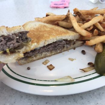 Dan's Diner - Best Patty Melt and fries I've had anywhere! - A partially eaten cheeseburger with melted cheese and beef patty, served with French fries and a pickle on a white plate. - Diners Near Me - Warren, Michigan