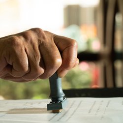 Maryland Neighborhood Notary - Picture of a man's hand holding a stamper notarizing a document.