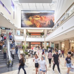 Chandler Fashion Center - Shoppers walk near the Scheels entrance, escalators and large digital display at Chandler Fashion Center.