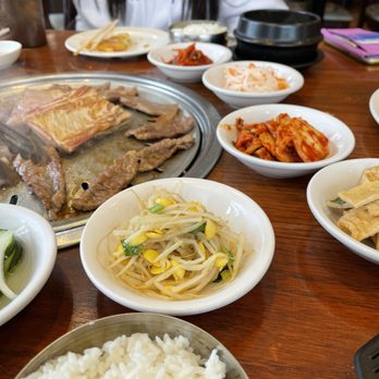 Seocho Garden - a woman sitting at a table with plates of food - Korean Near Me - Lisle, Illinois Seocho Garden - a woman sitting at a table with plates of food - Korean Near Me - Lisle, Illinois
