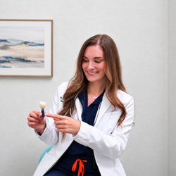 Edge Dental Designs - Dr. Elena Nemirovskii uses a tooth model to explain dental implant restorations and tooth replacement options in McKinney, TX.