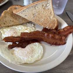 Eggs over medium with bacon and rye toast.