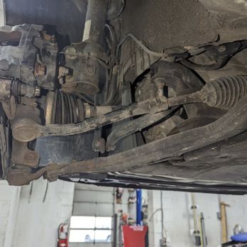 Tires Plus - Not done at all, tie rod - View of a vehicle's suspension and steering system, including tie rods and control arms, in a garage setting. - Tires Near Me - Onalaska, Wisconsin