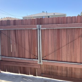 Adar Builders - Repaired gate - A double wooden gate reinforced with metal bars and cables, installed between a concrete wall on the left and a wooden fence on the right. - General Contractors Near Me - Winnetka, California