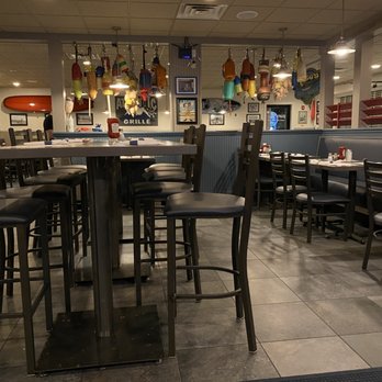 Atlantic Grille - The image shows the interior of a seafood restaurant featuring nautical-themed decorations, including hanging buoys. There are tables and chairs arranged for dining, with some tables set with condiments. - Breakfast & Brunch Near Me - Middletown, Rhode Island