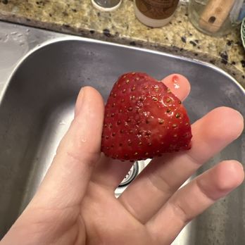 Albertsons - a hand holding a strawberry in a sink - Grocery Near Me - San Marcos, California