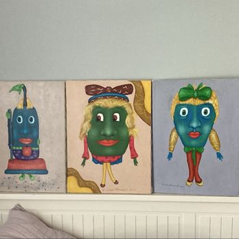 Ultimate Treasures - Five painted wooden plaques with anthropomorphic faces and colorful designs are displayed on a wall above a bed. - Antiques Near Me - Downers Grove, Illinois