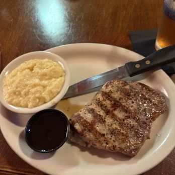 The Yearling Restaurant - Prime Pork Ribeye with cheese grits and house salad (not pictured) served with cranberry raspberry sauce - Southern Near Me - Hawthorne, Florida The Yearling Restaurant - Prime Pork Ribeye with cheese grits and house salad (not pictured) served with cranberry raspberry sauce - Southern Near Me - Hawthorne, Florida