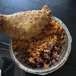 Papivivi - Cheese empanada on top of a side of yellow rice and beans.