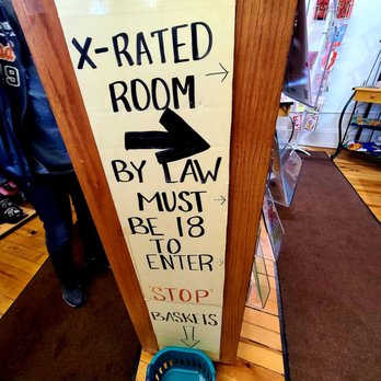 Breaking Bad - A tall wooden sign with handwritten black and red text provides directions to an X-rated room, requiring legal age, with arrows pointing right and down. - Art Tours Near Me