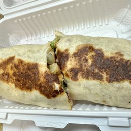 Grilled Chicken - A large grilled wrap with a browned, crispy exterior, partially open to reveal vegetables inside, placed in a white takeout container.