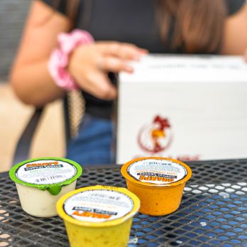 Champs Chicken - a woman sitting at a table with three cups of food - Fast Food Near Me - Peoria, Illinois
