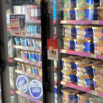Kwik Star - The ice cream and the frozen perishables pizzas etc - A refrigerated display case contains various frozen dairy products, including ice cream tubs and frozen pizzas, with a sign indicating a hiring opportunity. - Convenience Stores Near Me - Davenport, Iowa