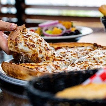 Valentino's - a person taking a slice of pizza - Italian Near Me - Fremont, Nebraska Valentino's - a person taking a slice of pizza - Italian Near Me - Fremont, Nebraska
